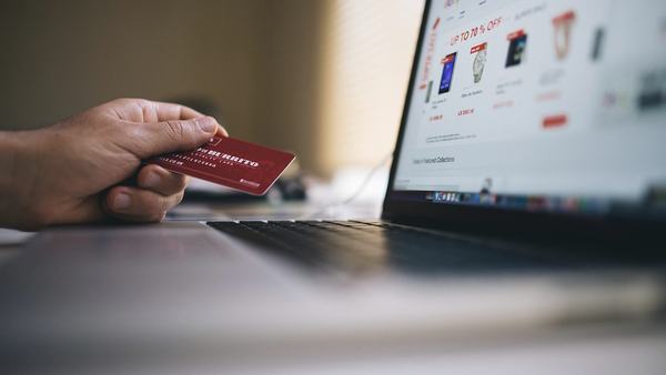 Hand holding a credit card beside a laptop
