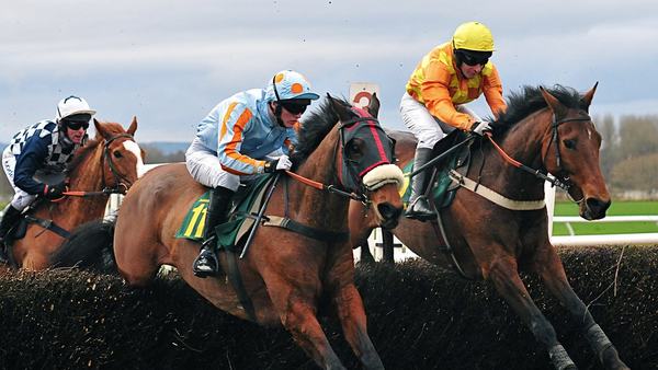 Racehorses and jockeys clearing a fence